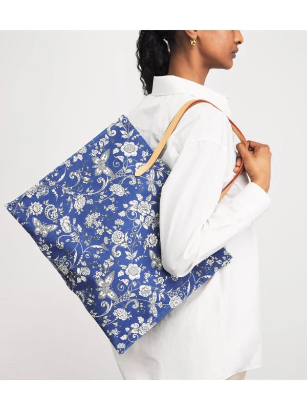HARRODS Large Cotton Butterfly Tote Bag_4 Harrods 藍色女用托特包印花細節特寫,布滿精緻花朵與蝴蝶,並點綴經典金色 Harrods 字母商標