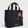 HDBA2622004 Harrods 藍色重磅厚帆布手提包正面,展示英國勳章軍服絲帶花與亮片徽章細節