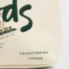 HDBE2630008-00_4 Harrods 城市故事帆布化妝包整體平放,米白底色搭配倫敦地標與 Harrods 門面圖案